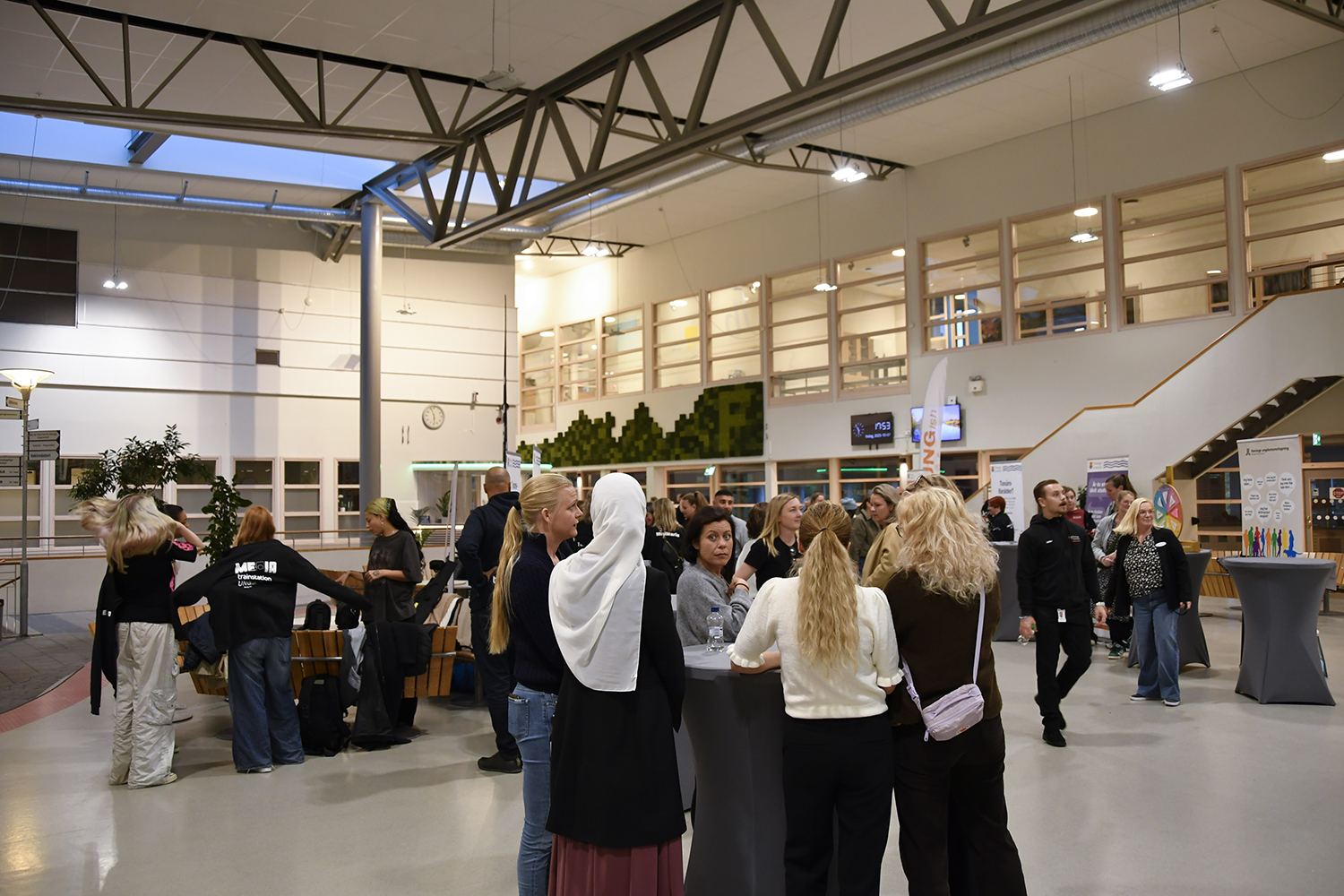 Översiktsbild från evenemanget med minglande deltagare i en ljus inomhusmiljö på Fredrika Bremergymnasiet med högt i tak och stora fönster.