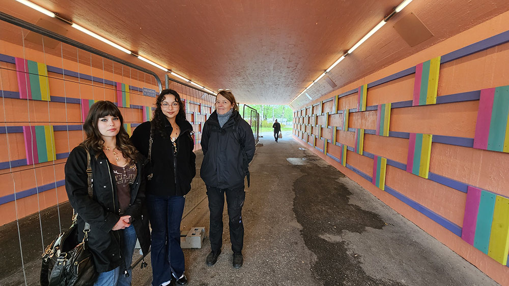 Personer som står tillsammans i en gångtunnel som är målad i aprikos-rosa färg