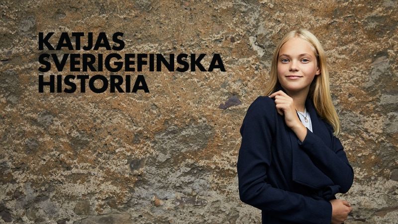 Flicka i svart tröja står framför en stenvägg och ler mot kameran