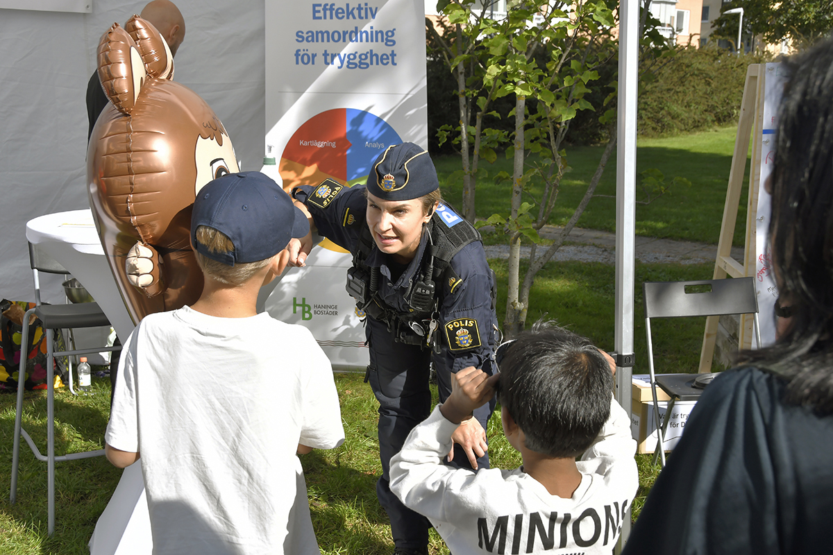 En polis pratar med två barn som håller en stor ballong vid ett trygghetsevenemang i Haninge.