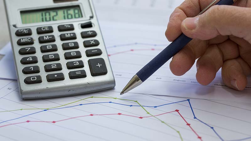 Penna på papper med graf, miniräknare i bakgrunden
