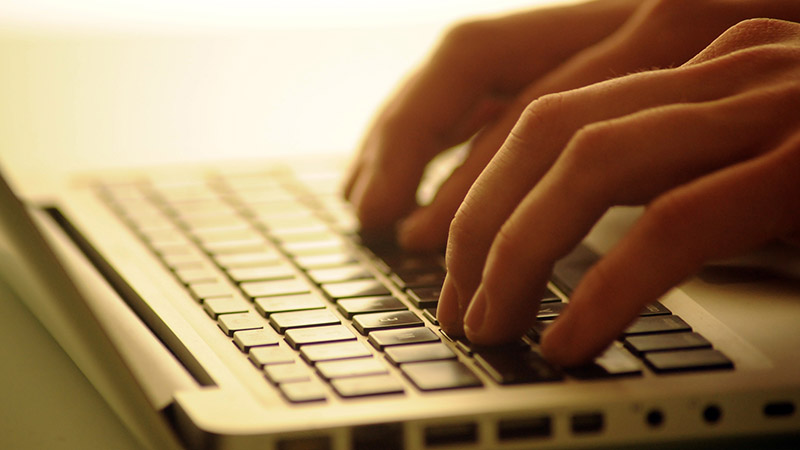 Två par händer som skriver på ett tangentbord