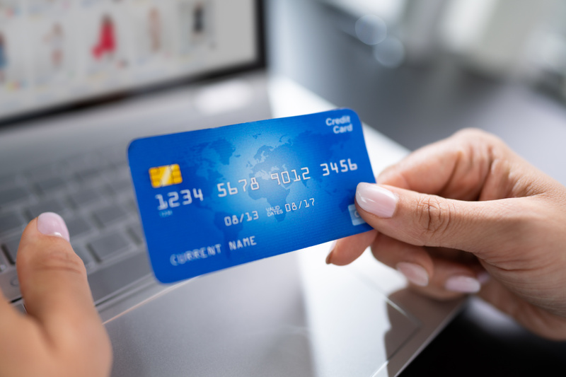 kvinna vid tangentbord håller upp ett kontokort