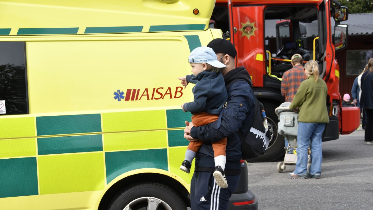 Pappa och pojke tittar på ambulans och räddningsfordon.