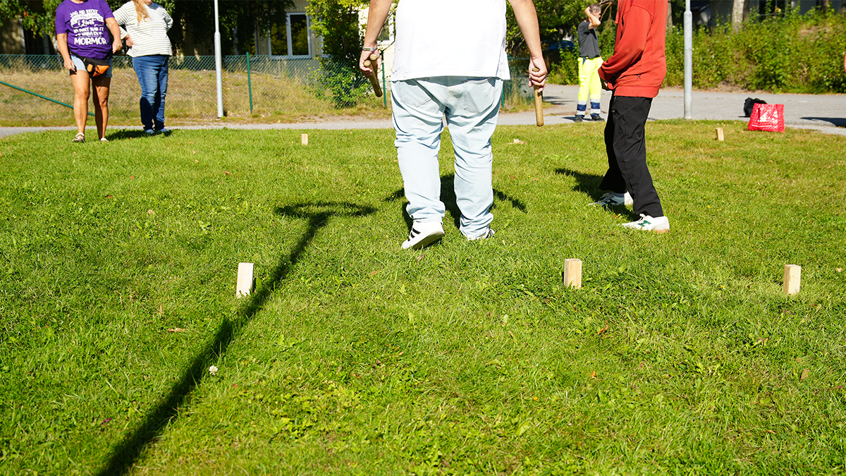 En grupp spelar kubb på en gräsmatta.