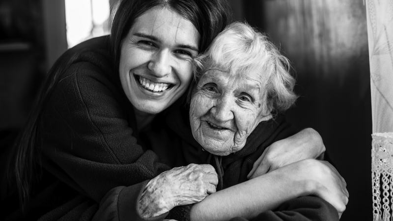 Ung kvinna omfamnar en äldre kvinna