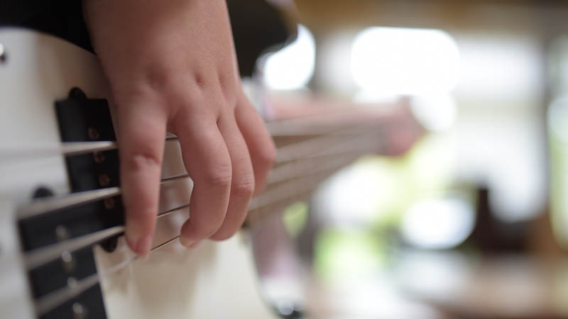 En närbild på ett barn som spelar elgitarr